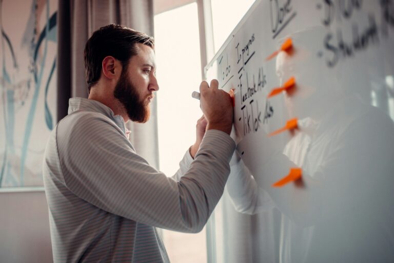 Man writing a plan on a whiteboard in an office