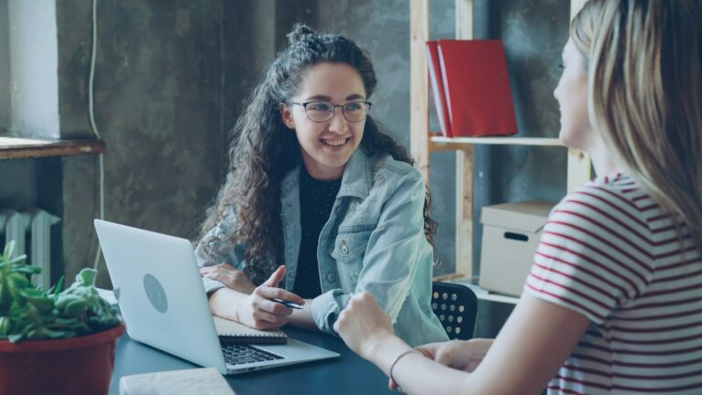 Two women in a friendly client consultation at a desk
