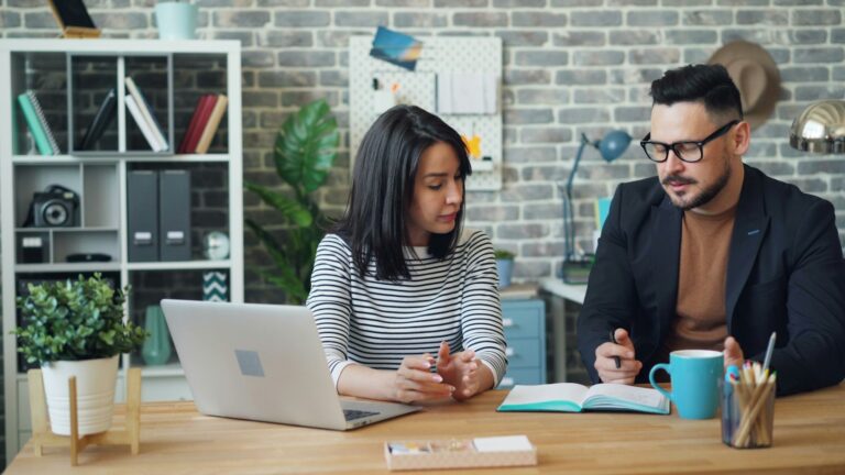 A man and a woman reviewing a laptop together at a table