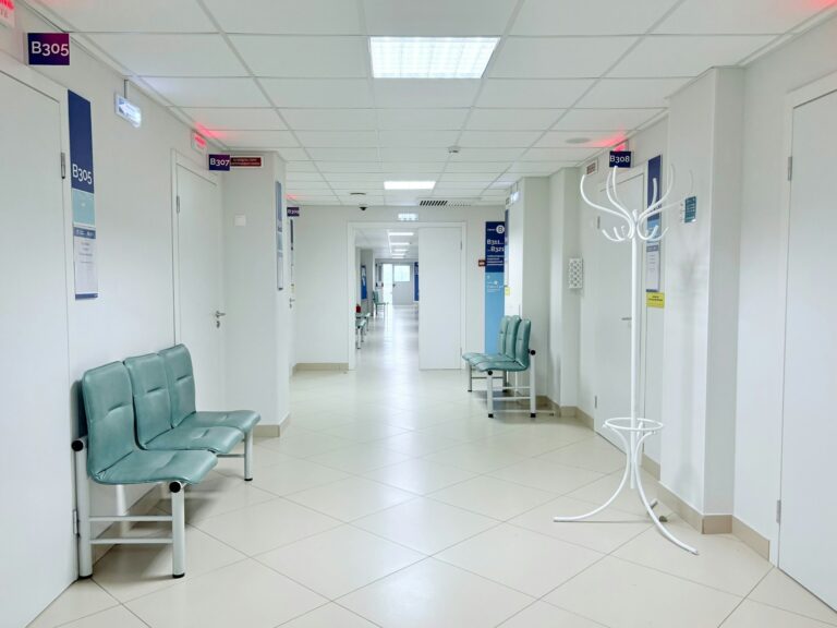 Bright hospital corridor with benches and doors