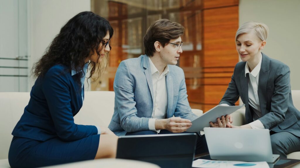 Three professionals discussing a contract around a table in a meeting room